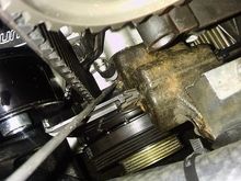 Using a hooked rod to take the slack out of the timing belt without removing the crank pulley.