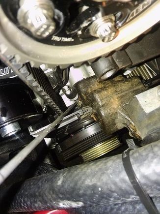 Using a hooked rod to take the slack out of the timing belt without removing the crank pulley.