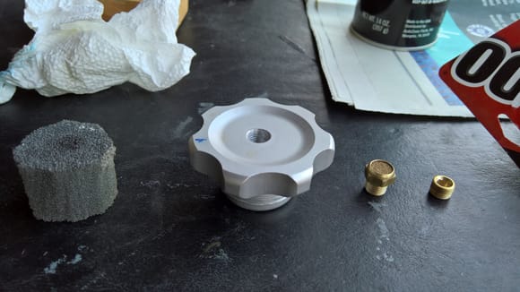 My first attempt at fixing the axle breather leak. From left-to-right: Part of an old sanding block, the filler cap, the original vent breather removed, and a plug to fill the original breather hole. In this pic, I have drilled and tapped the center of the cap to accept the breather vent. 