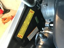 See the smaller white “Shell” sticker beneath the yellow “High Voltage” warning sticker.  Located along the driver’s side of the engine bay.