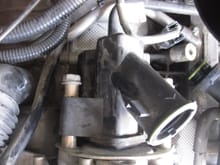 It is hard to see here, but there is a hard tube that enters the back of the power steering pump.  You need to push in the red seal fitting and pull the hose out.  I cut a semi circle in the edge of a hard plastic scraper and used it to push in the red seal.