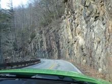 Narrow twisty road to Highlands with close by rock walls.