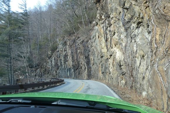 Narrow twisty road to Highlands with close by rock walls.