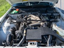 Engine compartment showing magnesium (tan) intake and all factory parts (strut brace, decals, etc.) intact. Fiberglass hood has original "kickstand" in place. 