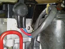 Another view of the bottom, to the right is the booster pump.  The pump is note leaking, the area by the blue and red wires is wet with fluid.  It is possible that the MC is leaking between the two pieces of aluminum blocks.  The area in the middle of the red loop, which is a brake line that connects the booster to the MC. A bolt can be seen in the lower left.