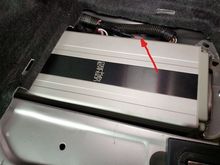 Right/Passenger's side vent is behind the harness, arrow points to its top rear edge.  The aft amp bracket's 10mm nut is at right, there is a similar nut under the carpet to the left.  Once the nuts are removed, the entire amp can be removed and/or rotated out of the way.  Make sure to place the harnesses on *top* of the plastic cable tray under the amp before reinstalling.  AMHIK.  