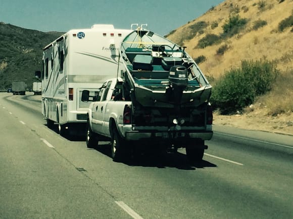 Motor home towing a full size truck with boat in the bed going over the Grapevine in CA