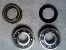 Old original bearing (left) with black dusty grease; one of the budget replacement bearings on the right overfilled with grease