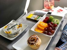 Fruit plate, yogurt, cinnamon roll. 