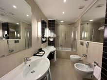 The bathroom has a bathub, a bidee and two sinks.