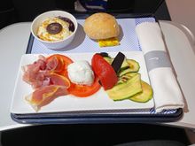 Prosciutto, mozzarella, tomato and roast vegetables, bread roll and a blueberry cheesecake dessert (?)