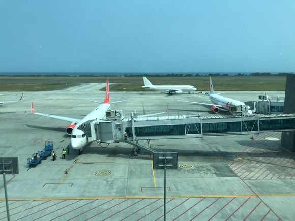 The airport uses aerobridges,
In the far distance you can see the ocean,
It is paralel to the runway