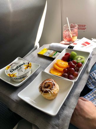 Fruit plate, yogurt, cinnamon roll. 