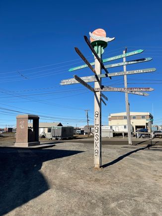 Will Rogers / Wiley Post memorial to the left of the totem signpost with distances to various places.