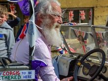 The 'Royal Mobility Car', sponsored by The Village Bar in Weston Sub-Edge. License plate HRH 70. See the sign: 'ONLY CORGIS TO BE TETHERED HERE'. He had his flag-waving teen granddaughters ride with him, wearing royal masks.