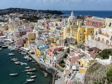 The iconic belvedere vista of Corricella. Amid the pastel buildings, yellow chiesa S. Rocco looms large. Nearby, S.M. delle Grazie, Casale Principe Umberto and Palazzo Mignano de Iorio. 