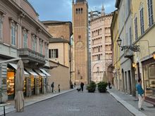 Parma in the early evening with the Battistero, Bell Tower, and Duomo at the end of the street. 