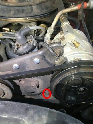 Red circle at head of long bolt that passes through a pipe-like spacer and into the cylinder hed