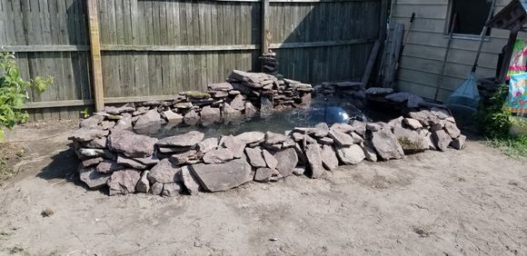 Two layers of stone first, pulled the liner up over those layers and continued layering stone. Built it up in the back and added a water fall using the filter pump. Done! We added 4 tadpoles, 7 Comets, lillies, and couple other things.