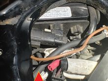 Red arrow pointing to black cable is audio harness.  Two wires split off and go to positive and negative on battery.  Brown cable is hanging free here under seat, no crimp or covering, wire looks clipped.