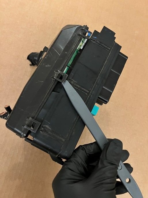 3 clips on left side. 1 more clip on rear not shown. 6 clips total hold bottom cover to fuse box body.