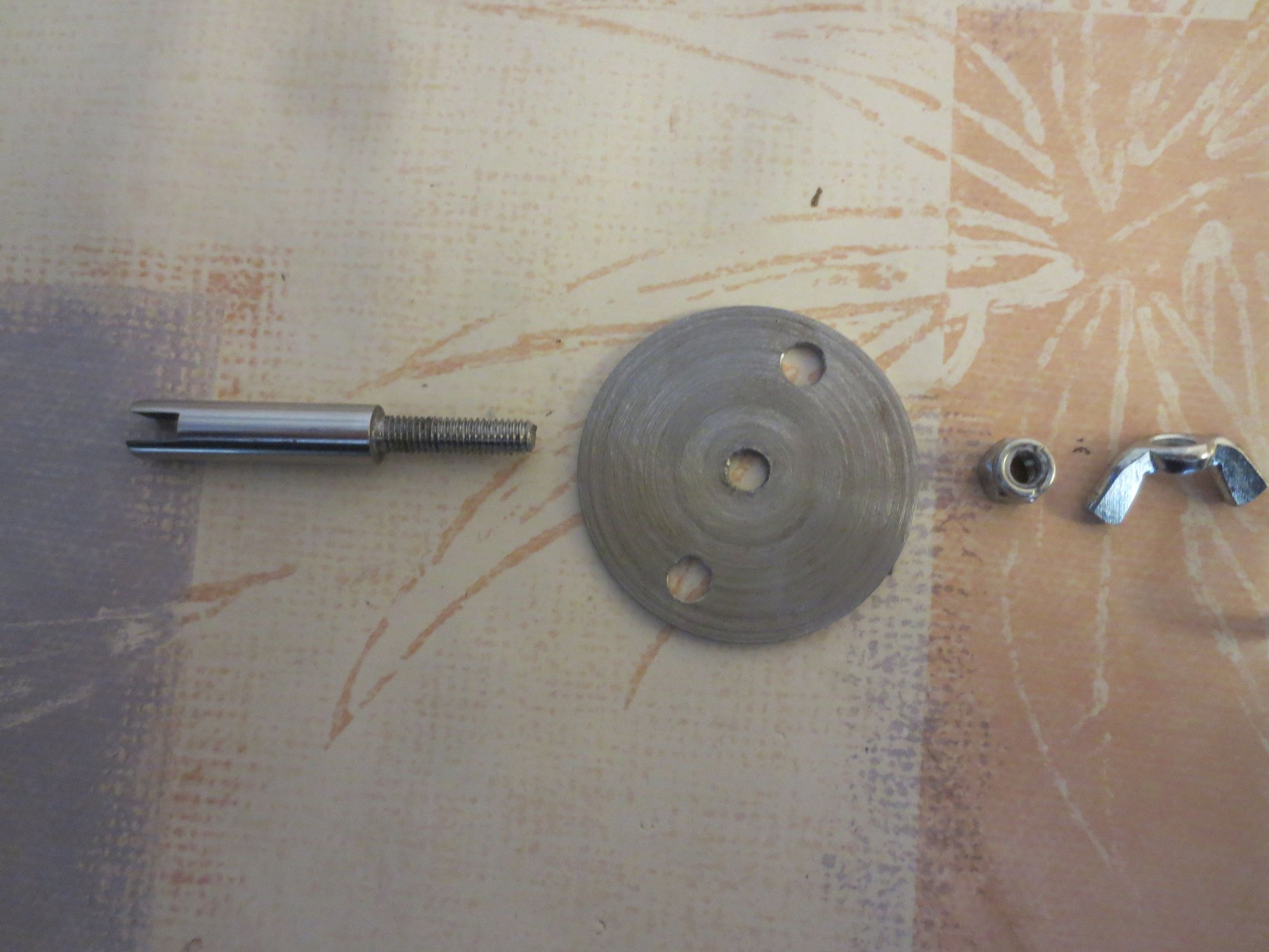 From left to right: Shouldered spindle with 5mm threaded top, disc, locknut to lock disc to spindle shoulder, wingnut to be attached to threaded part with permanent Loctite 270 to act as adjuster and counter-torque when doing up the locknut.