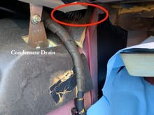 Condensate drain location, passenger footwell compartment carpet removed.  Speculation: one may be able to access this without removing the carpet.