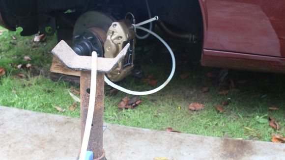 Have the Tube hanging down in a 'U' Bend with 'The Jack Stand' Higher than the Caliper Bleed Nipple