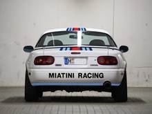 Again, the Miatini logo adds width. A circumferential blue stripe connects both sides of the car.