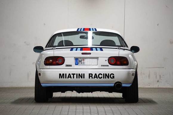 Again, the Miatini logo adds width. A circumferential blue stripe connects both sides of the car.