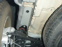 Next to spare on drivers side, empty space where the muffler is on the other side