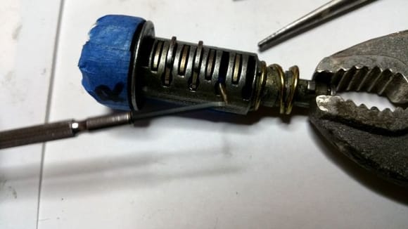 With a little ingenuity (and even littler tools), I managed to remove the remminant dust door spring as well as all the pins and their cooresponding springs from my original lock cylinder...
Pictured above: I began transferring all my original pins in cooresponding order, into the salvage cylinder barrel. Using a small magnetized flathead jewelers screwdriver, made it much easier to load in those near microscopic pin springs.