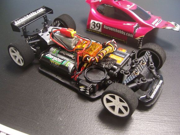 Penny's car with the body off of it. Most of us are using li-po now but to some extent the AAs are still better for our application. The AA batteries gave us over 2 hours straight of run time but they just take up to much space. The li-po batteries still have tons of run time (well over 1 hour) with our low power setups. Some of us are using brushless but the brushed speed controls still seem to give us the best throttle response. Speed is limited and matched between the cars using the transmitters EPA adjustment. You can see our old custom motor mount (we've made a new and much better mount out of carbon fiber) and our custom designed leaf spring suspension. Our suspension offers absolutely ZERO friction in the suspension unlike the stock springs. The result is a car that drives straight, corners smoothly and handles consistently! There were some other updates to the springs that aren't in this picture as well. We're also using the "pro" Xray foam tires now. Another huge upgrade is in the works and the first prototype was cut out of carbon fiber from the CNC machine not to long ago. It will give us (and anyone else) much more options for the chassis layout along with some other body options in the future.