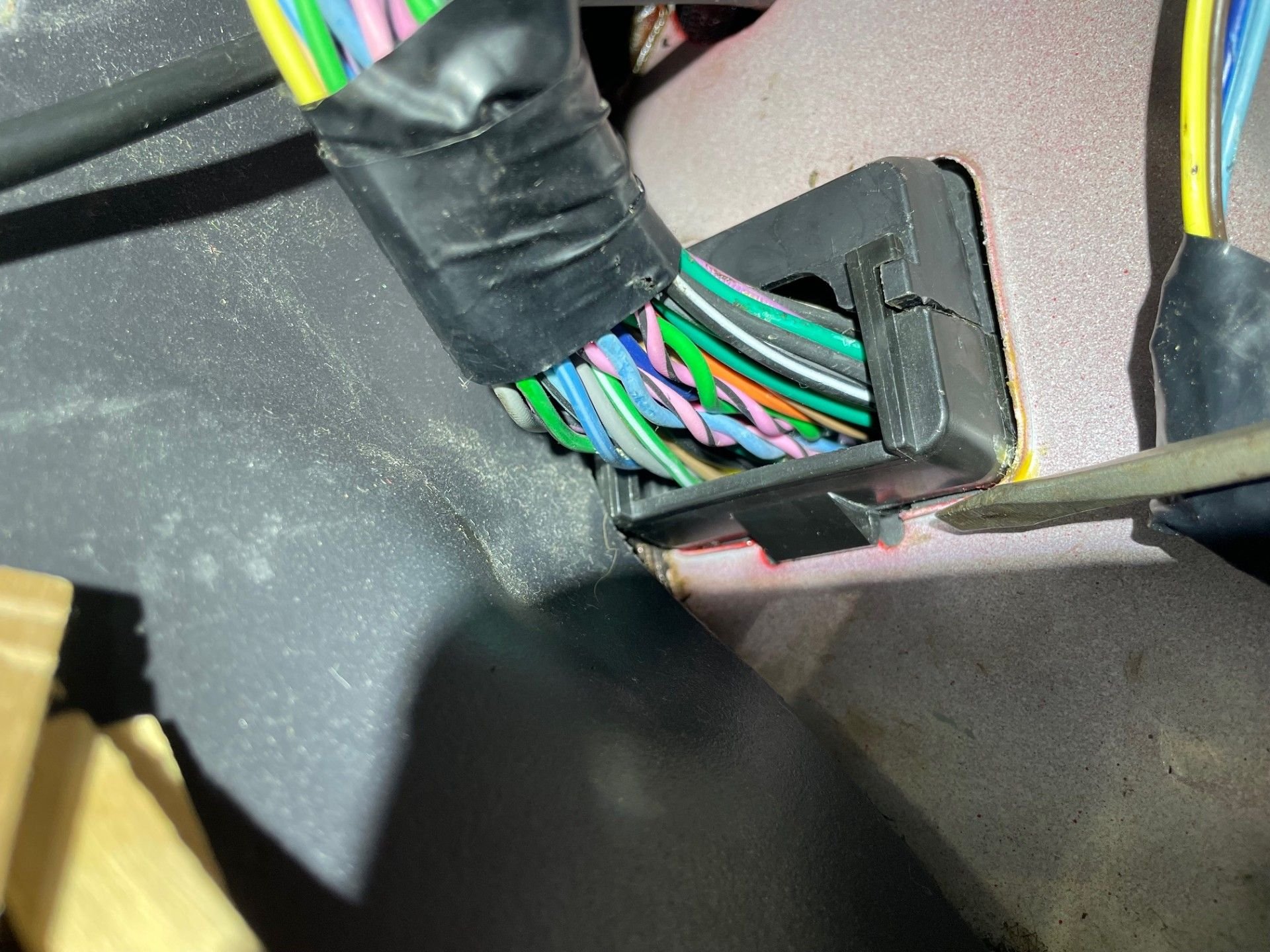 The screwdriver is pointing to a tab at he bottom.  There is no way to squeeze this or push it up to allow the connector to go through the sheet metal.