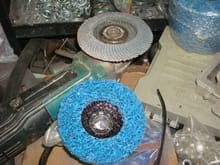 Electric angle grinder. The disc on it is a flap disc for grinding welds but the blue disc below it is for paint. 